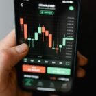 Hand holding smartphone displaying cryptocurrency trading graph in app.